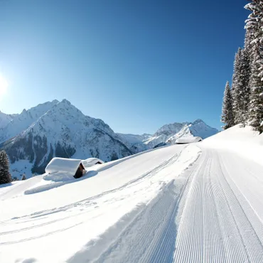 7 for 6 winter offer Groomed ski slope with snowy alpine huts and mountain landscape under clear blue sky